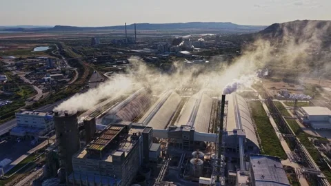 Factory in operation with smoke and steam rising into the sky Stock Footage 341329400