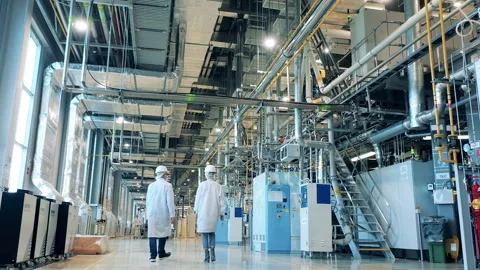Factory premises with pipes and two specialists walking through Stock Footage 166902970