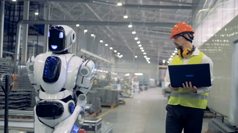 Factory robot pulls a platform truck, while man watches it working. Video stock 88996209