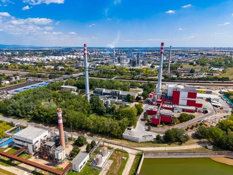 Factory site with large chimneys and green areas located near a city during.. Stock Photos