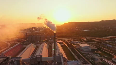 Factory with smoke and sunset over hills in the background Stock Footage 340945614