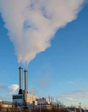 Factory with smoke exiting chimney. Stock Photos