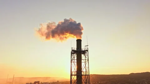 Factory smoke stack releases steam during sunset over a manufacturing area 動画素材 340945551
