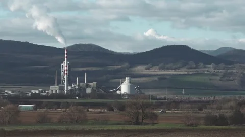 Factory with smoking chimney in front of winter mountain landscape Stock Footage 325823576