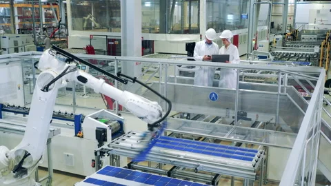 Factory unit with two specialists and a robot relocating solar panels Video stock 164654575