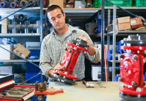 Factory worker assembles shutoff valves using various tools indoor Stock Photos