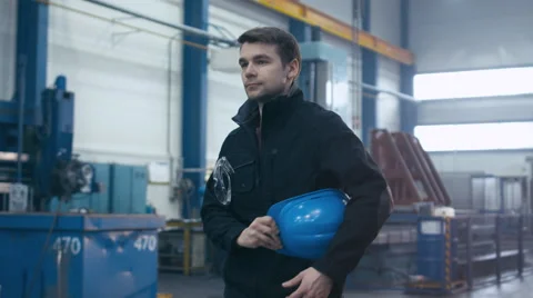Factory worker in blue uniform is putting his hard hat and goggles on Stock Footage