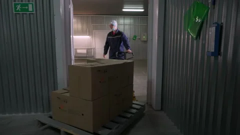 Factory worker carrying a cart filled with cardboard packaging storage boxes Stock Footage 253174364