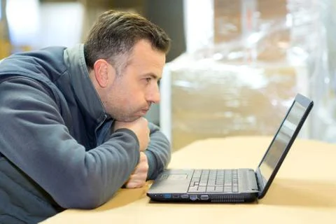 Factory worker in-charge of packing looking at laptop Stock Photos