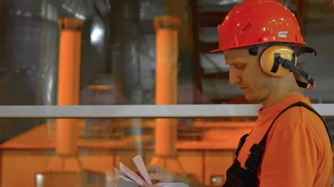Factory worker cross-checks data with checklist during night shift. Ensuring Stock Footage 280499614