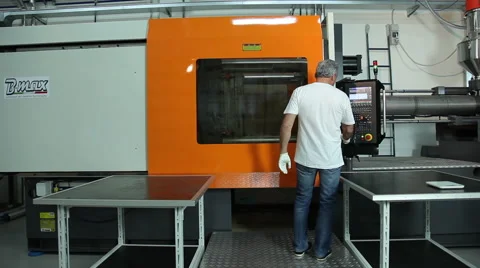 A factory worker demonstrates how to operate a heavy piece of equipment. Stock Footage 64093307