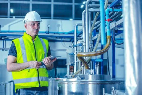 Factory worker engineer working in factory using tablet computer to check mai Stock Photos