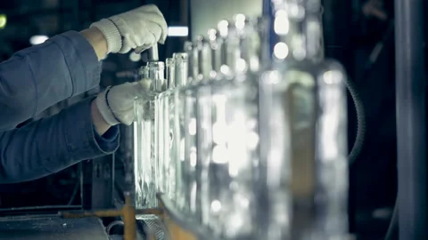 A factory worker examines bottles' neck on a conveyor at a plant. 4K. Stock-Footage 88709734