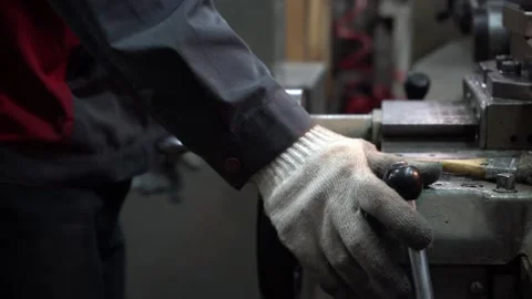 Factory worker in gloves manually operating lathe machine Stock Footage 323301268