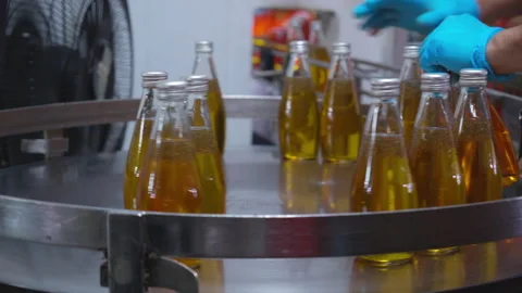 Factory worker hand checking glass bottles with yellow liquid fruit juice b.. Stock Footage 334582751