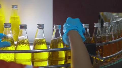 Factory worker hand checking glass bottles with yellow liquid fruit juice b.. Stock Footage 334582933