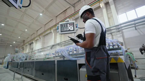 Factory worker in a hard hat and uniform is using a tablet with an engineering 動画素材 270104785