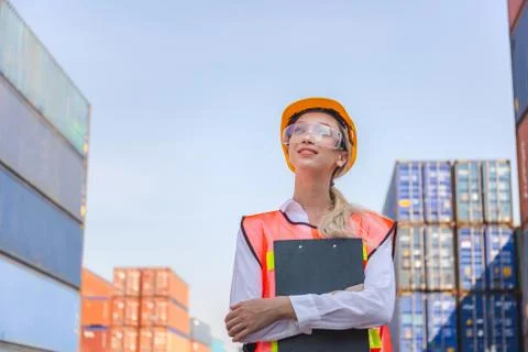 Factory worker in hard hat smiling and looking to the sky at containers cargo 写真素材