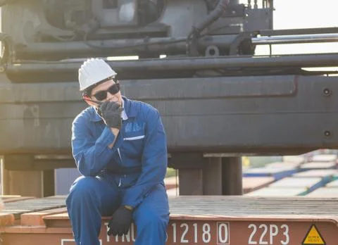 Factory worker in hard hat talks on two-way radio control loading containers Fotos Stock