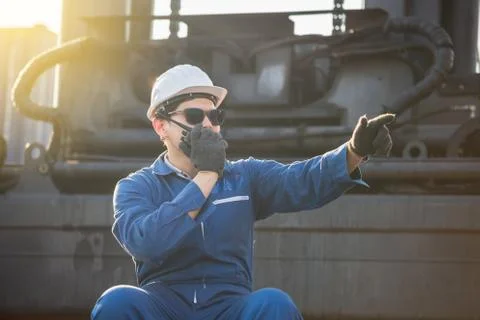 Factory worker in hard hat talks on two-way radio control loading containers Фото