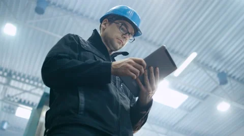 Factory worker in a hard hat is using a tablet computer Video stock 61881796