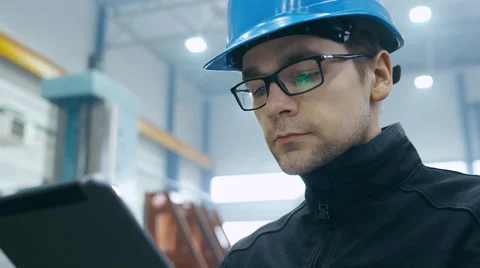 Factory worker in a hard hat is using a tablet computer 動画素材 61881923