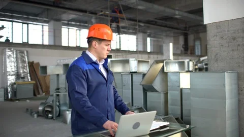 Factory worker in a hard hat is using a laptop computer with an engineering 動画素材 85817936