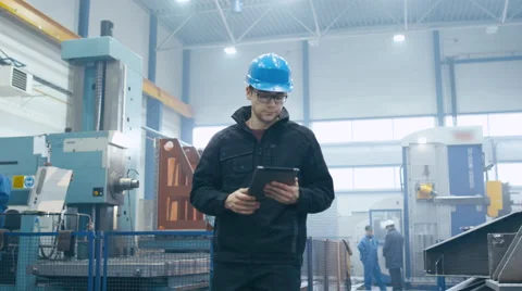 Factory worker in a hard hat is walking and using a tablet computer Video stock 61881980