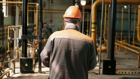 Factory worker in a hard hat is walking through industrial facilities. Rear view Stock-Footage 170323607