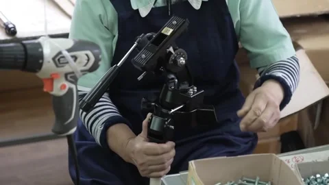 Factory worker holding assembled black equatorial mount head with cordless Stock Footage 334964643