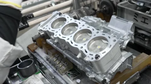 Factory worker inspecting the cylinders of an aluminum engine block and Video stock 333399441