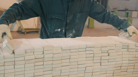 Factory worker in jumpsuit gathers white concrete bricks Video stock 124003280