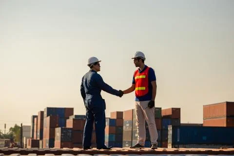 Factory worker man and engineer handshake on cargo container evening sky blur Фото