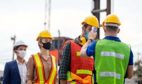 Factory worker man checking fever by digital thermometer for scan and protect Фото