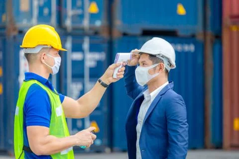 Factory worker man checking fever by digital thermometer for scan and protect Фото