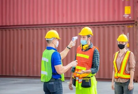 Factory worker man checking fever by digital thermometer for scan and protect Fotos de archivo