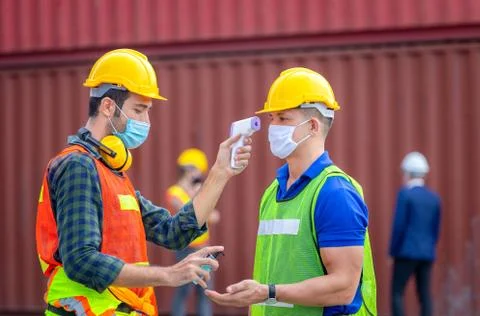 Factory worker man checking fever by digital thermometer for scan and protect Fotos Stock