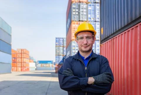 Factory worker man in hard hat smiling with arms crossed at container cargo Foto stock