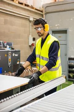 Factory worker moving wood panel on conveyor belt Foto stock