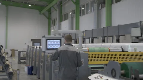 Factory worker operates and controls large roll making machine Stock Footage 290508315