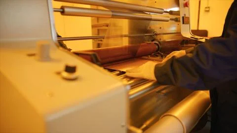 Factory worker operating industrial laminating machine processing copper foil Stock Photos