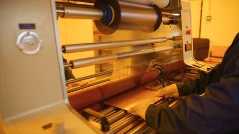 Factory worker operating industrial lamination machine processing copper foil Stock Photos