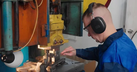 Factory worker operating industrial press machine in manufacturing workshop Stock Footage 338253737