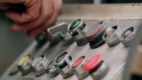 A factory worker operating knobs and dials on a metal grinding machine 動画素材 255216518