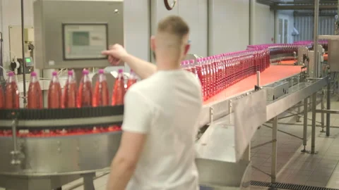 Factory worker operating touch screen control panel on automated bottling line Stock Footage 328608074
