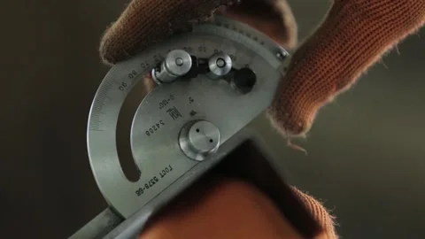 Factory worker in orange gloves measures metal detail angle Stock Footage 138879577