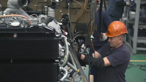 Factory Worker In Orange Helmet Assembling Parts Of Large Transport Vehicle Stock Footage 195618393