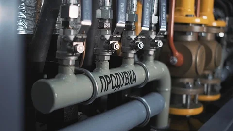 Factory worker in overalls interacting with pipes in an industrial room Stock Footage 125881388