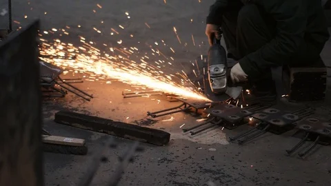 Factory worker polishes rebar elements with angle grinder Stock Footage 124608195