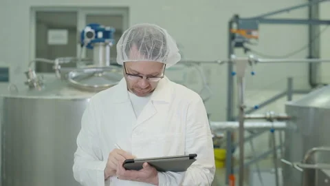 Factory worker presses multiple buttons on the tablet touchscreen with a stylus Stock Footage 224844590